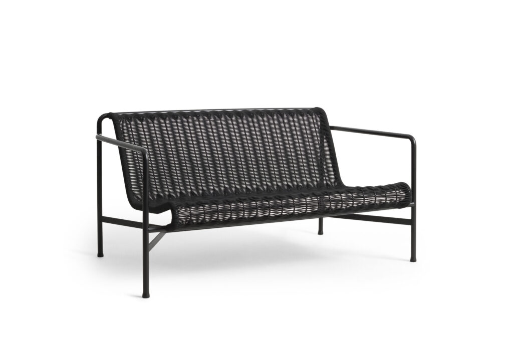 Un banc d'extérieur tressé noir avec une structure en métal et un dossier incurvé se dresse élégamment sur un fond blanc, dégageant une touche de sophistication anthracite.