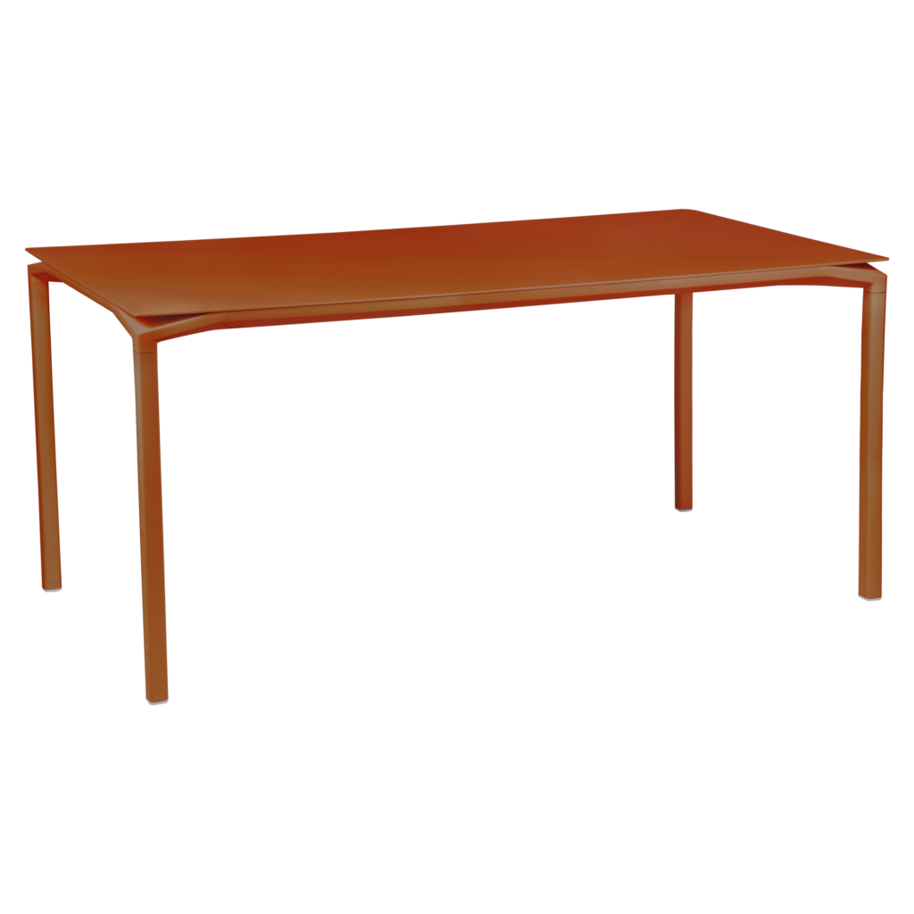 La table Calvi, d'un orange vif, mesure 160 x 80 cm et est dotée de quatre pieds fins. Son design minimaliste se détache sur un fond transparent, parfaitement mis en valeur par la teinte Bleu Maya, qui lui confère une touche d'élégance.