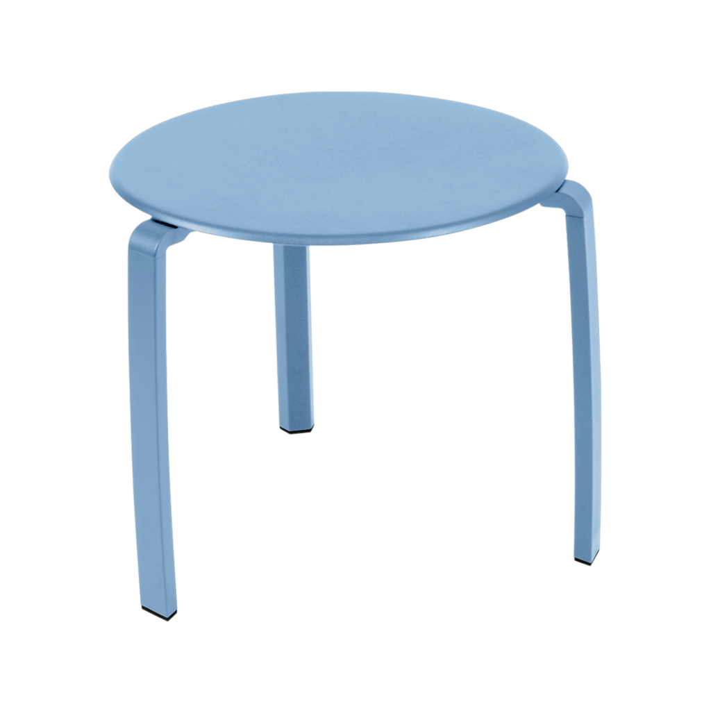 Un tabouret rond à trois pieds bleu clair à la surface lisse, posé sur un fond Bleu Maya assorti, évoque l'élégance d'une table basse Alize.