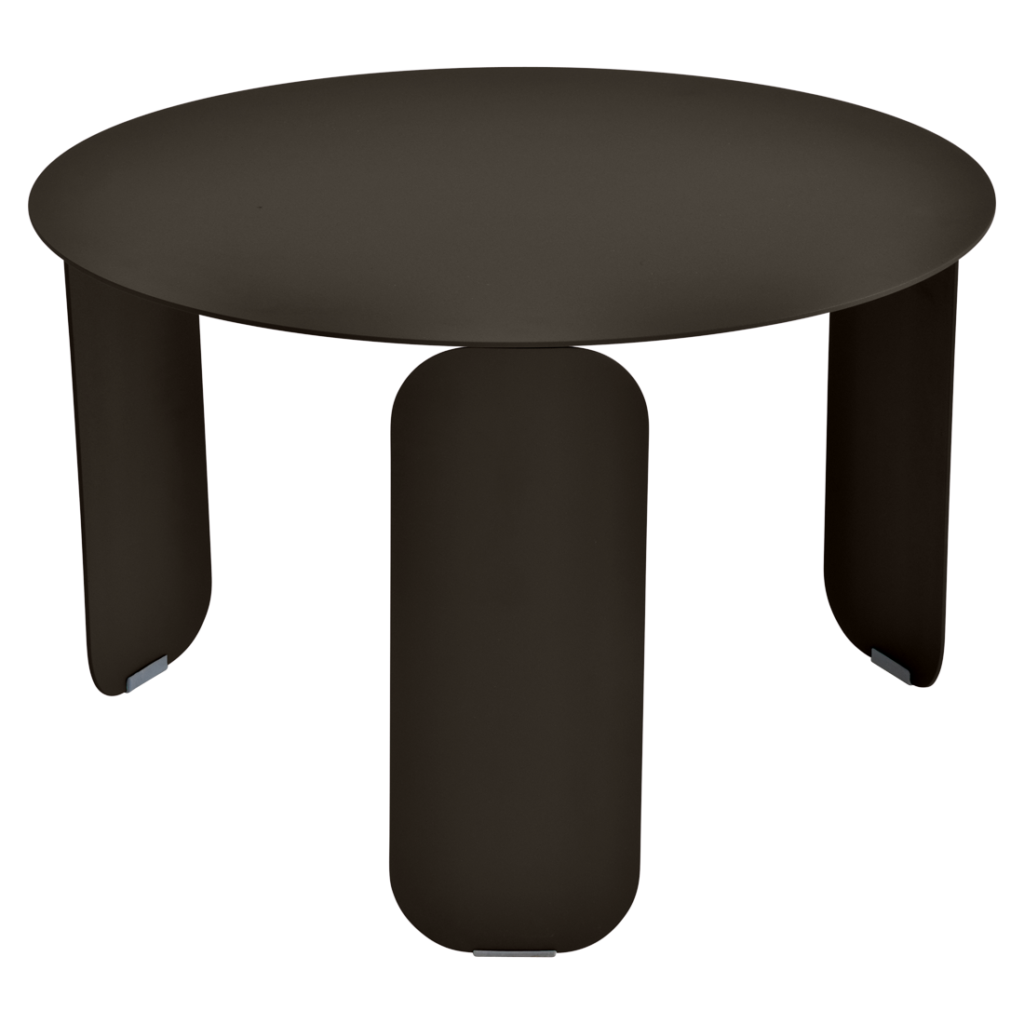 Une table basse ronde, marron foncé, avec trois pieds larges et plats, inspirés du style Bebop, posée sur un fond mauve clair.