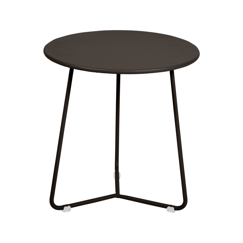 Une petite table d'appoint ronde noire aux pieds fins en métal se détache sur un fond violet clair, ajoutant une touche moderne rappelant le style Cocotte.