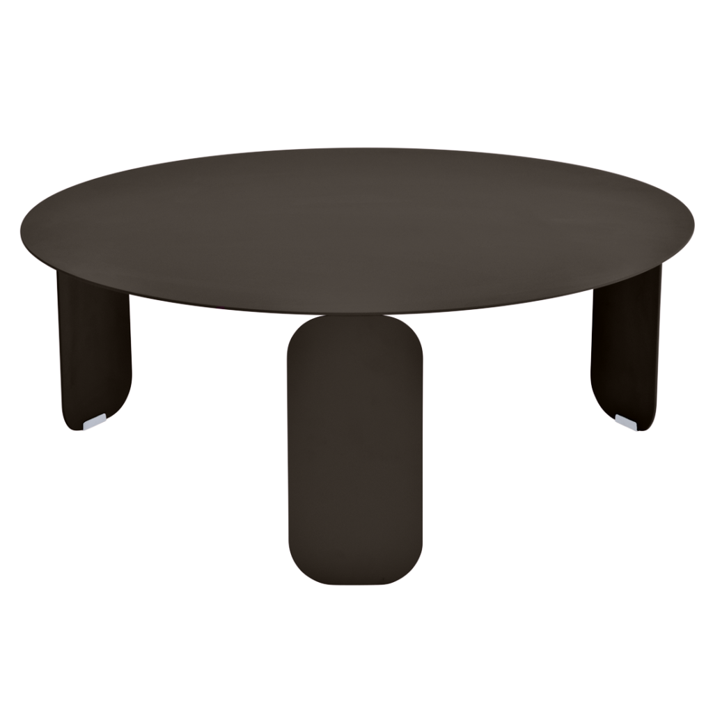 Une table basse Bebop ronde, marron foncé, avec trois pieds larges et arrondis, sur un fond violet clair.