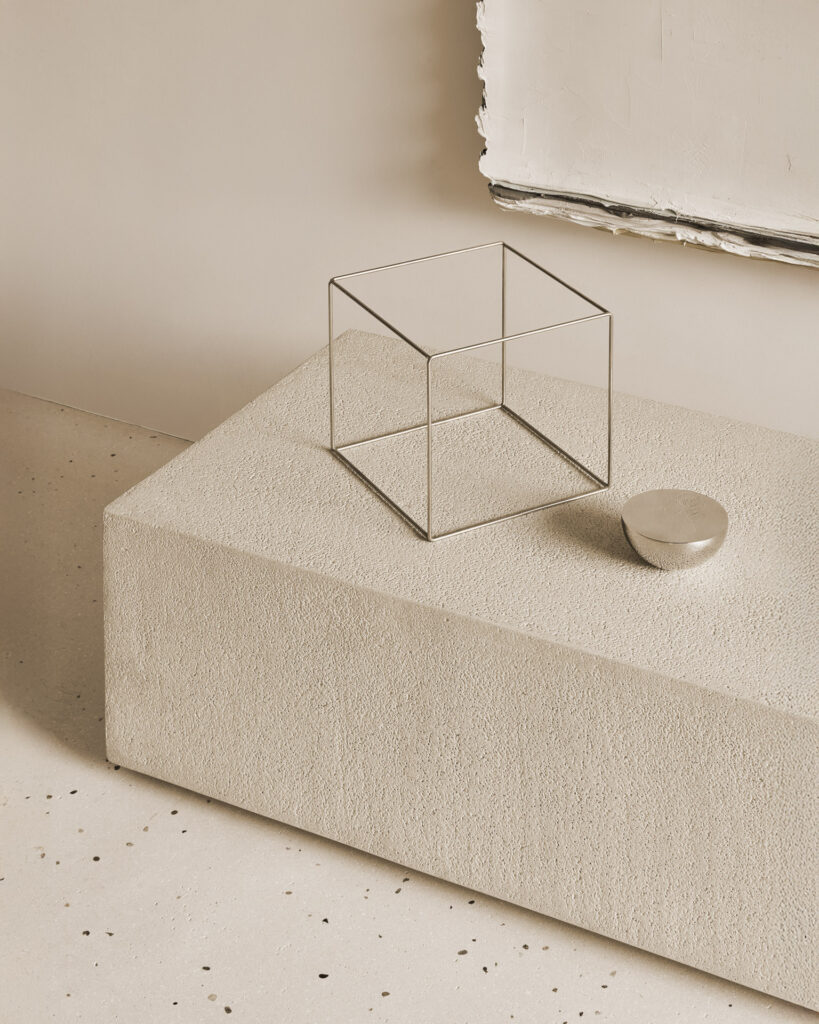 L'étagère au sol Elements présente un cube en fil métallique et un petit bol rond métallique sur sa surface texturée, sur un sol moucheté clair et un mur beige.