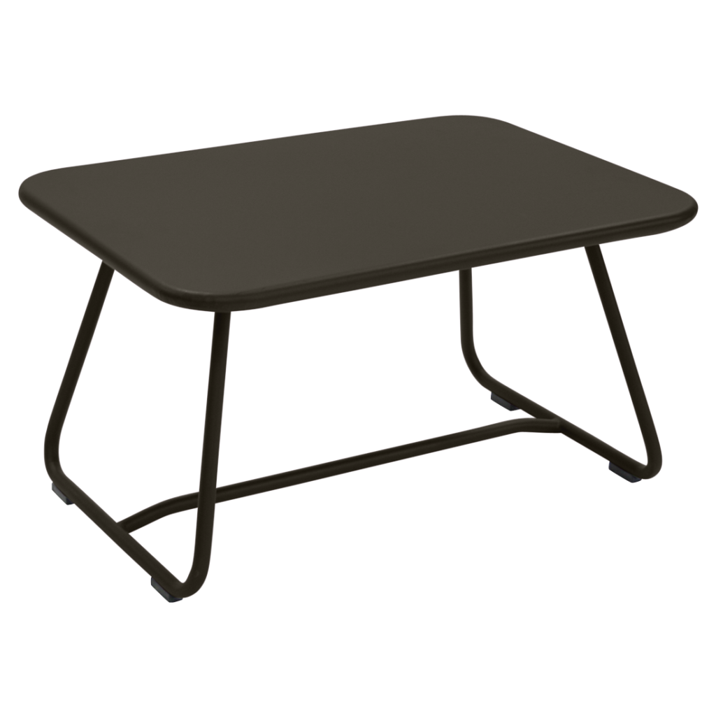 Une table basse rectangulaire noire aux bords arrondis et aux pieds en métal, inspirée des années 60, est posée sur un fond violet clair.