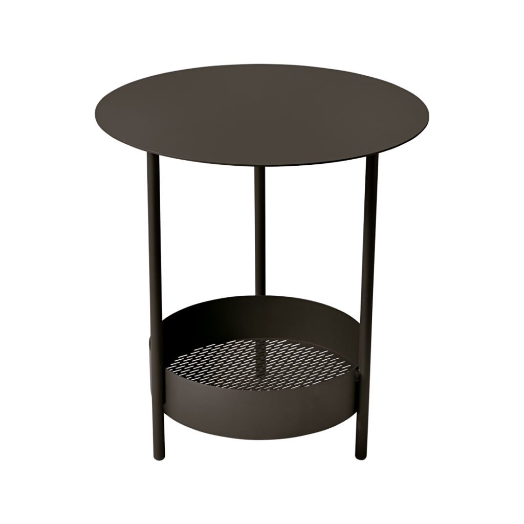 Table d'appoint ronde Guéridon Salsa en métal noir avec plateau inférieur en résille, positionnée sur un fond mauve uni.