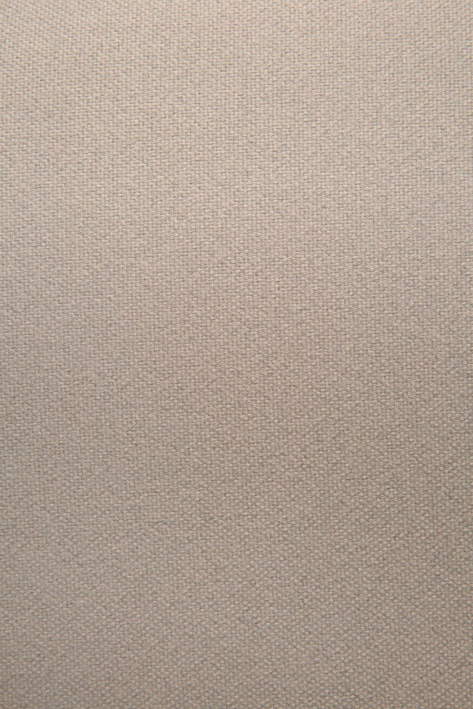 Gros plan sur le tissu marron clair à la texture subtile et uniforme de la chaise de salle à manger Unda. Ses tons chauds se marient à merveille avec sa structure en chêne, ajoutant une touche d'élégance à tout espace.