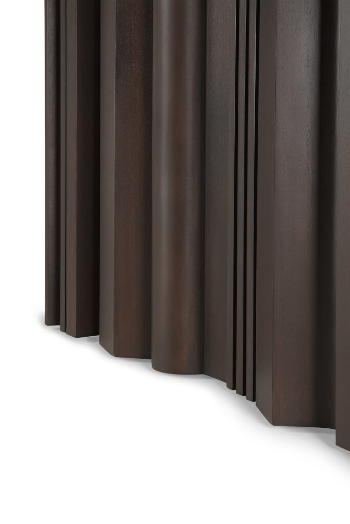 Gros plan sur la surface brun foncé de la table de salle à manger Sequence, qui présente des arêtes verticales et des colonnes légèrement arrondies de différentes largeurs.