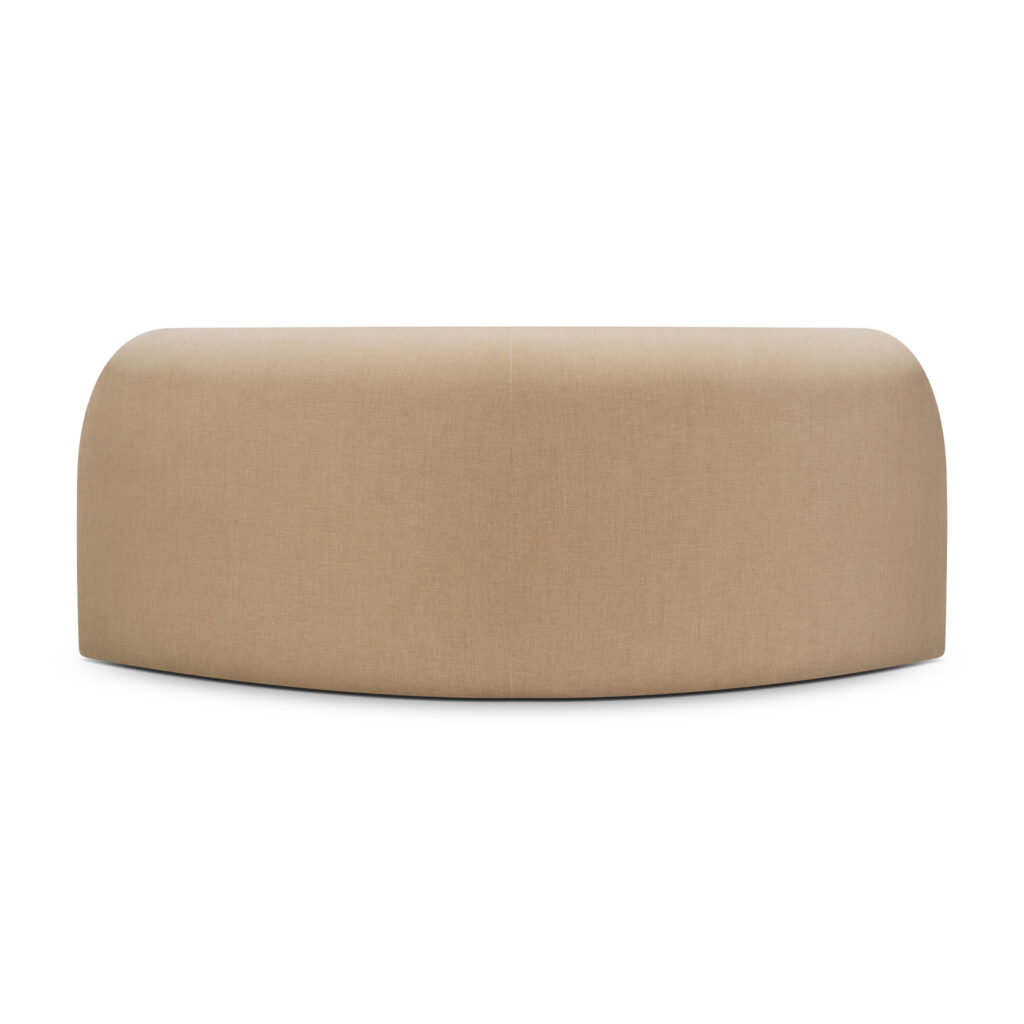 Un grand canapé volumineux et courbé recouvert de tissu marron clair, présentant une surface lisse et des bords arrondis, vu de face.