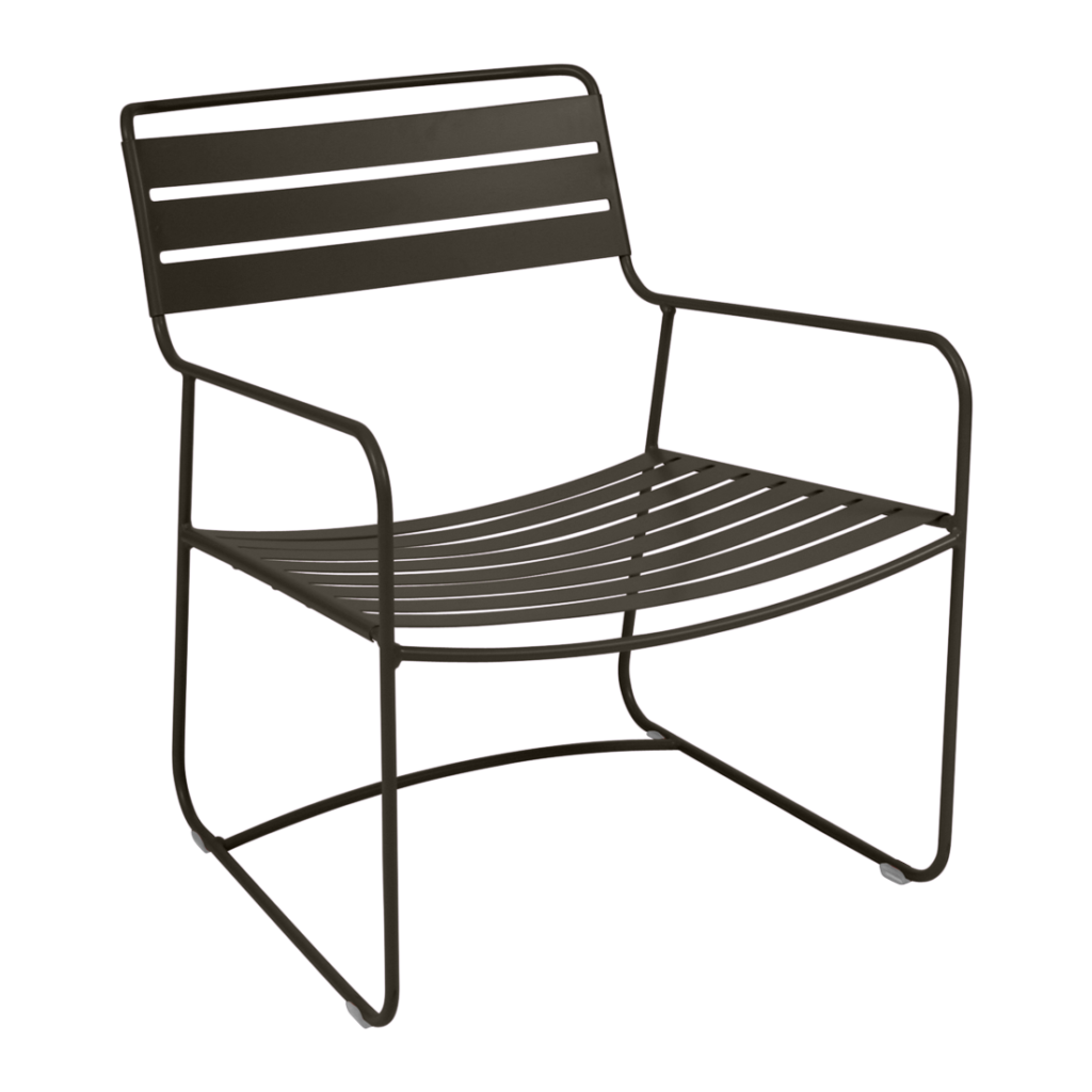 Surprenant fauteuil bas en métal noir avec assise et dossier à lattes, accoudoirs fins et design minimaliste, sur fond violet clair.