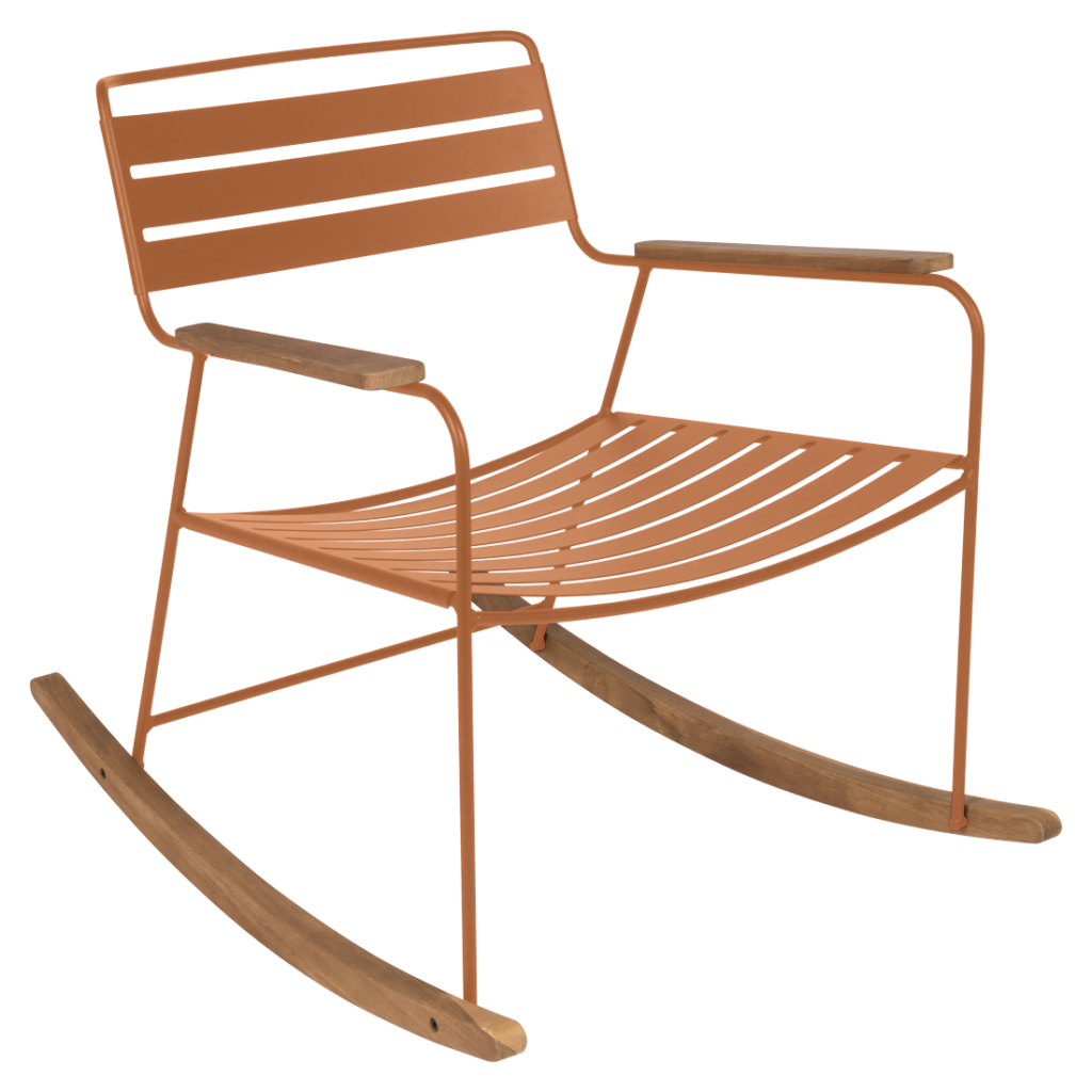 Une chaise à bascule en métal marron avec des accoudoirs en bois et des bascules en bois incurvées se dresse gracieusement sur un fond rose pâle, évoquant le charme intemporel de Bleu Maya.