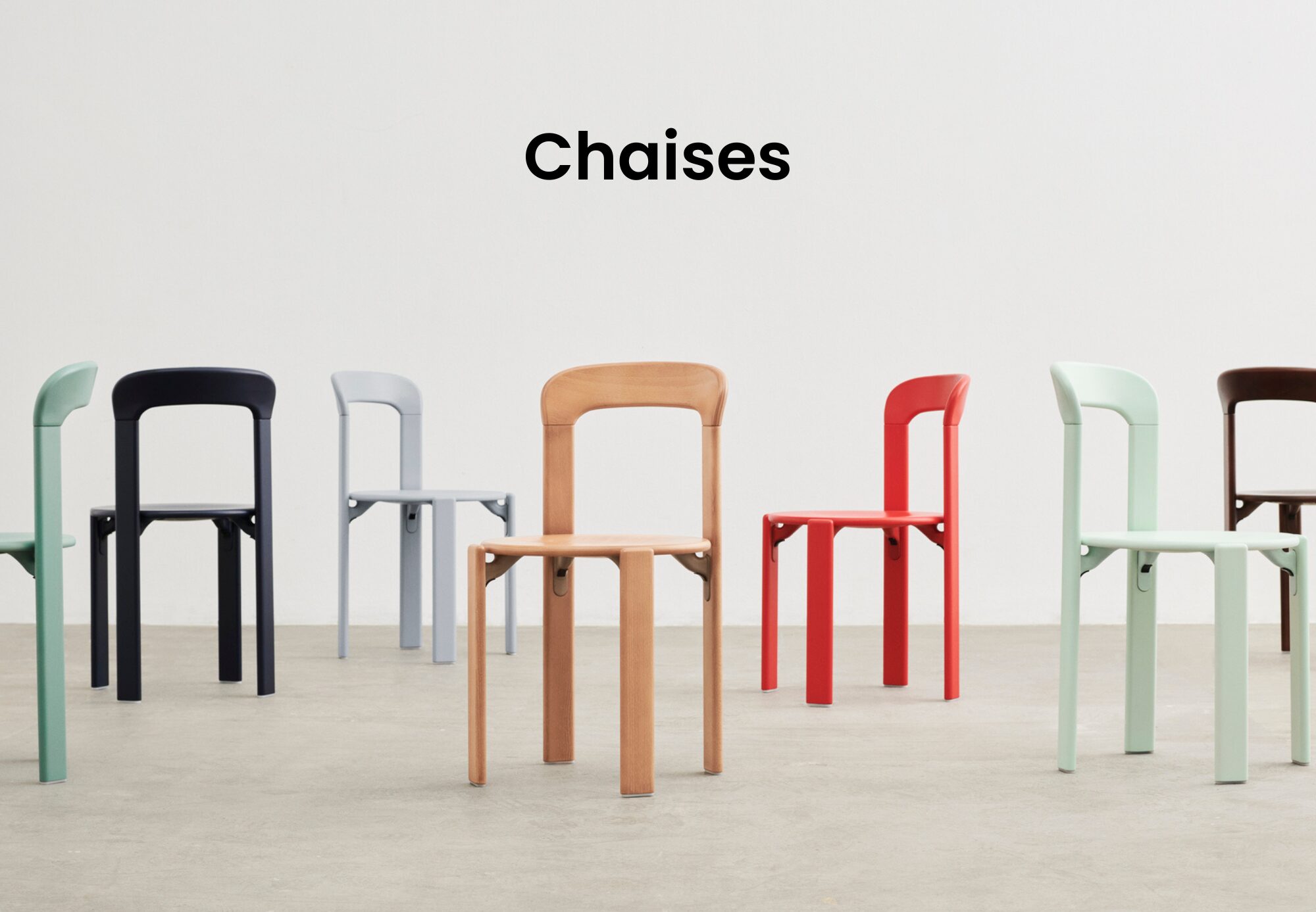 Six chaises modernes en noir, gris clair, bois naturel, rouge, vert menthe et sauge - chacune reflétant le design quatuor - sont disposées dans une pièce spacieuse avec un mur blanc étiqueté "Chaises" pour ce magasin de meubles design.