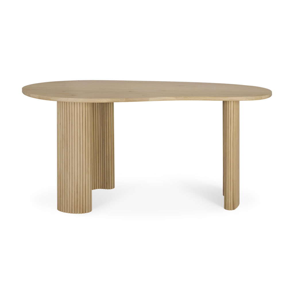 Table de salle à manger en bois clair avec un plateau ovale asymétrique, deux pieds cylindriques cannelés et un style Bureau Boomerang distinct, fabriquée en chêne naturel, sur un fond blanc uni.