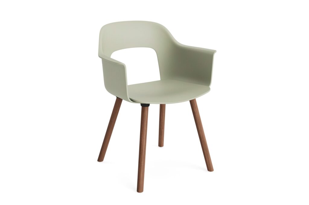 Fauteuil moderne avec une assise et un dossier en plastique vert clair, avec des côtés ouverts et quatre pieds angulaires en bois chêne laqué.