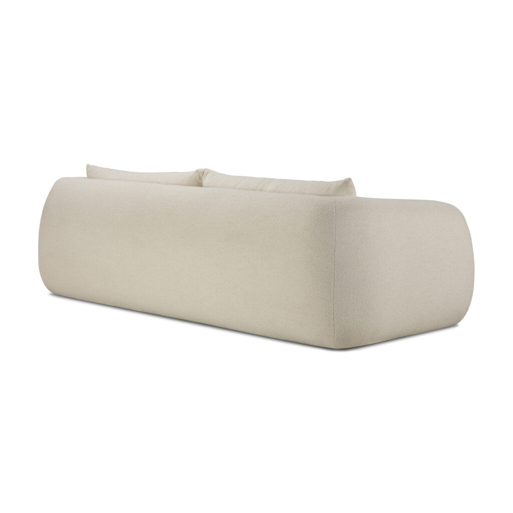 Le canapé Contour 3pl. est un canapé 3 places beige et moderne avec des bords arrondis, deux coussins de dossier et une surface en tissu rembourré montrée à l'arrière.