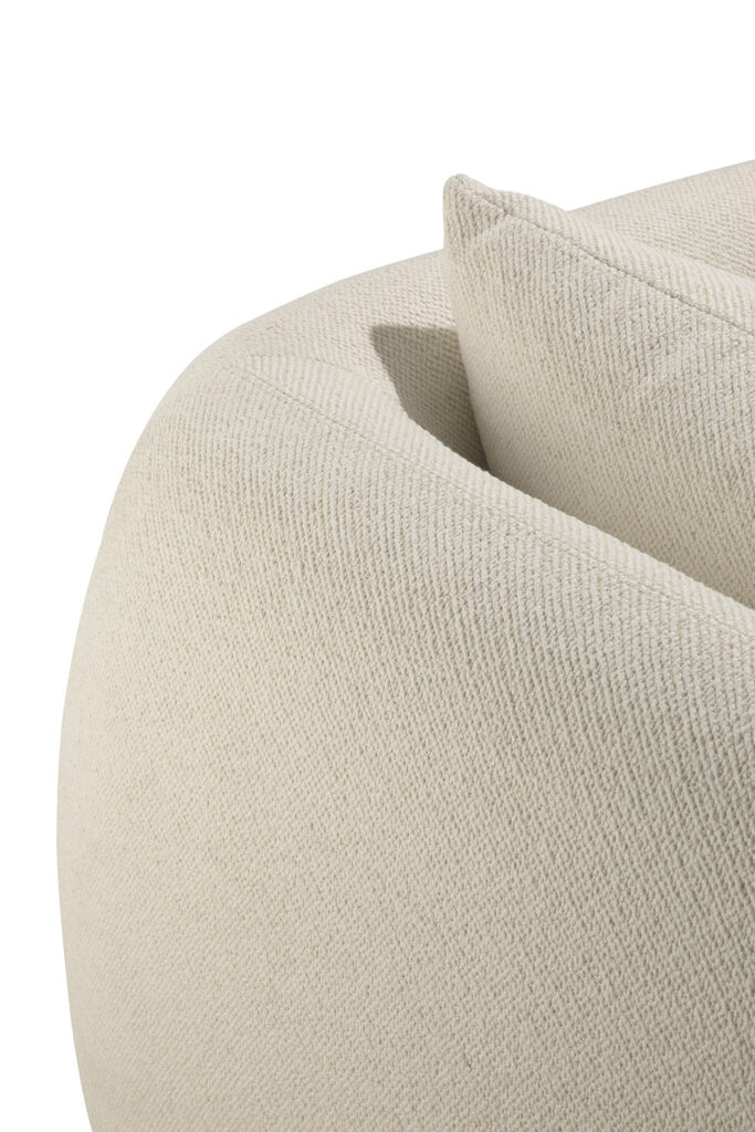 Gros plan sur le canapé Contour 3pl. en beige texturé avec un coussin assorti, mettant en valeur les détails de l'accoudoir et du dossier incurvés sur un fond blanc.