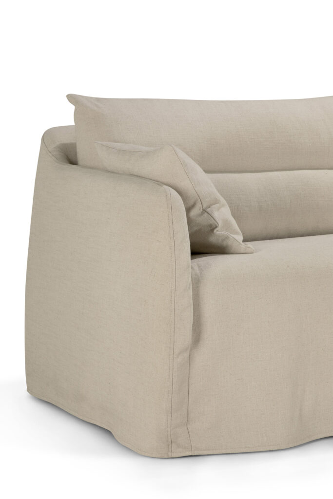 Vue rapprochée d'un canapé en tissu beige avec un coussin de dossier lâche et un accoudoir sur le côté gauche, mettant en valeur l'élégante texture de ce design en os 3pl.