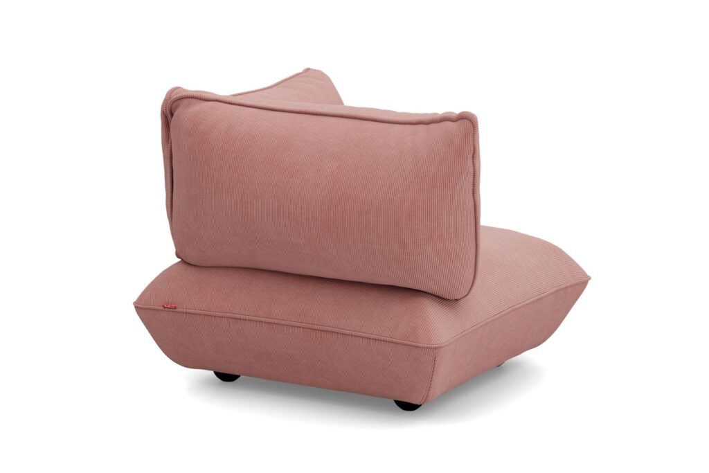 Le Sumo Corner Seat est un fauteuil d'angle moderne sans accoudoir avec un revêtement rose, un épais coussin d'assise, un dossier assorti et de petits pieds noirs.