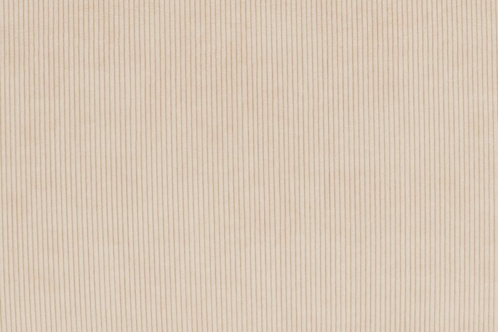 Gros plan d'un tissu côtelé beige avec des lignes verticales régulièrement espacées, ressemblant au revêtement du siège d'angle Sumo.