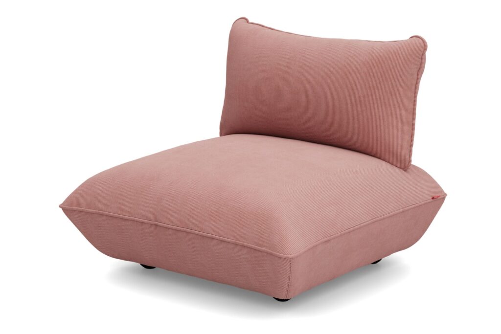 Chaise de salon moderne sans accoudoir à profil bas, recouverte de tissu rose, dotée d'un épais coussin d'assise en matériau recyclé Cord et d'un dossier légèrement incliné.