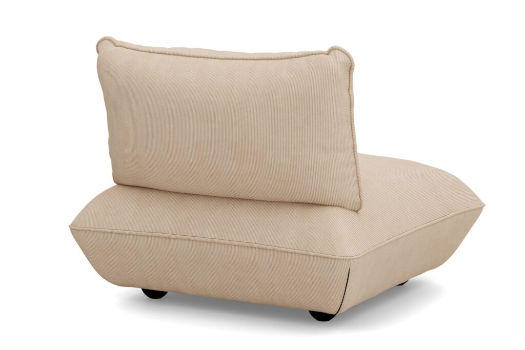 Une chaise longue beige sans accoudoir avec un coussin et un dossier épais offre une assise confortable, soutenue par de courts pieds noirs et présentée sur un fond blanc.