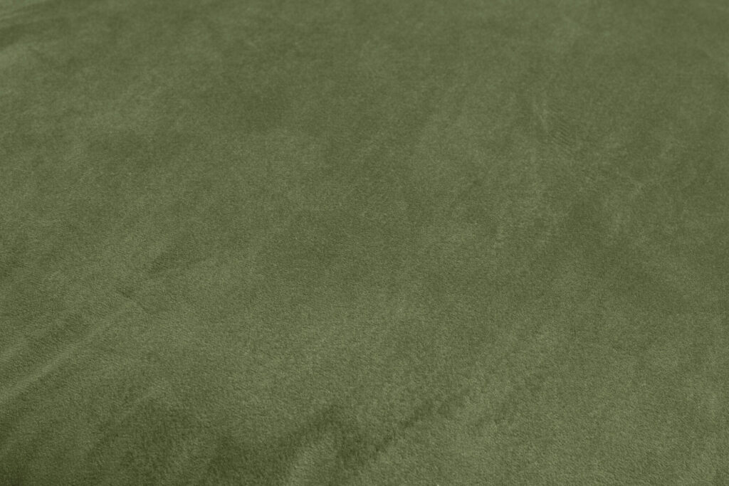 Gros plan sur la surface d'un tissu daim vert foncé, qui rappelle le velours des matériaux recyclés, montrant sa texture douce et ses subtiles variations de couleur, parfaites pour un siège Sumo.