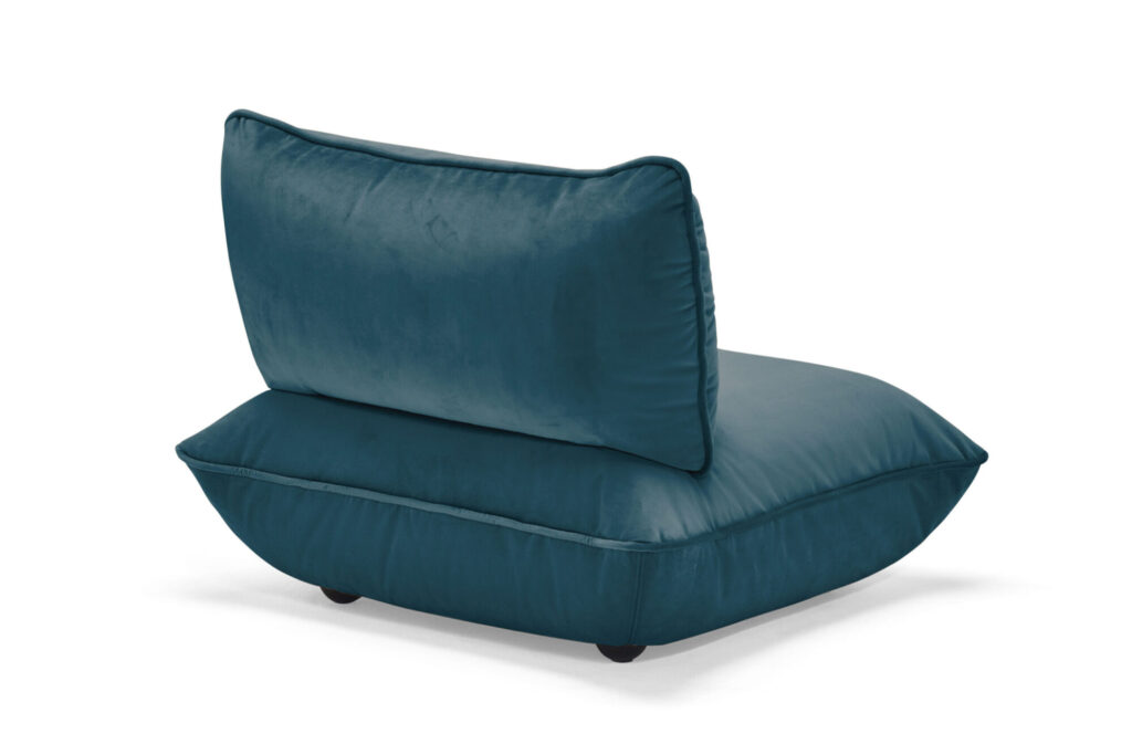 Chaise de salon moderne sans accoudoir avec un coussin rembourré en velours recyclé vert foncé et un grand dossier, positionné en angle sur de petits pieds noirs.
