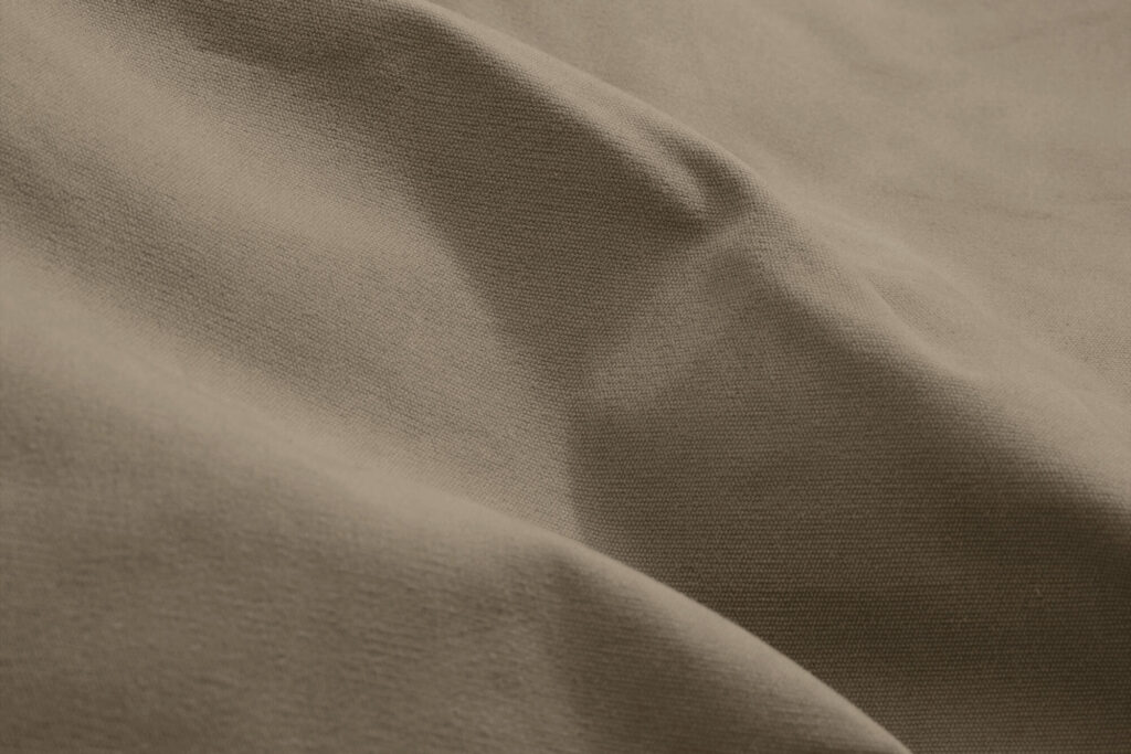 Gros plan sur un tissu gris taupe, rappelant Canvas Recycled, aux plis délicats et à la texture douce.
