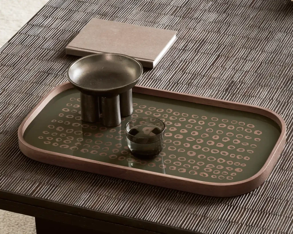 Le plateau rectangulaire en verre XL Second Nature Moss contient un verre foncé, un bol métallique à pieds courts et un livre, le tout disposé sur un plateau texturé.