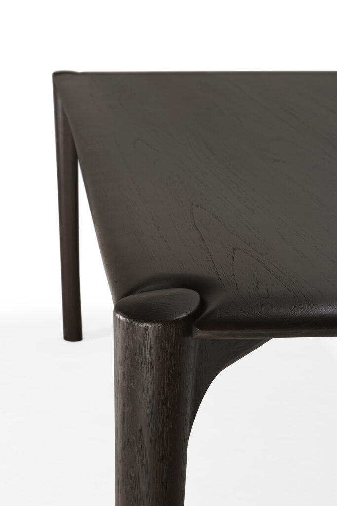 Vue rapprochée d'une table de salle à manger PI 140x80 aux pieds arrondis et à la surface lisse et polie, sur fond blanc.