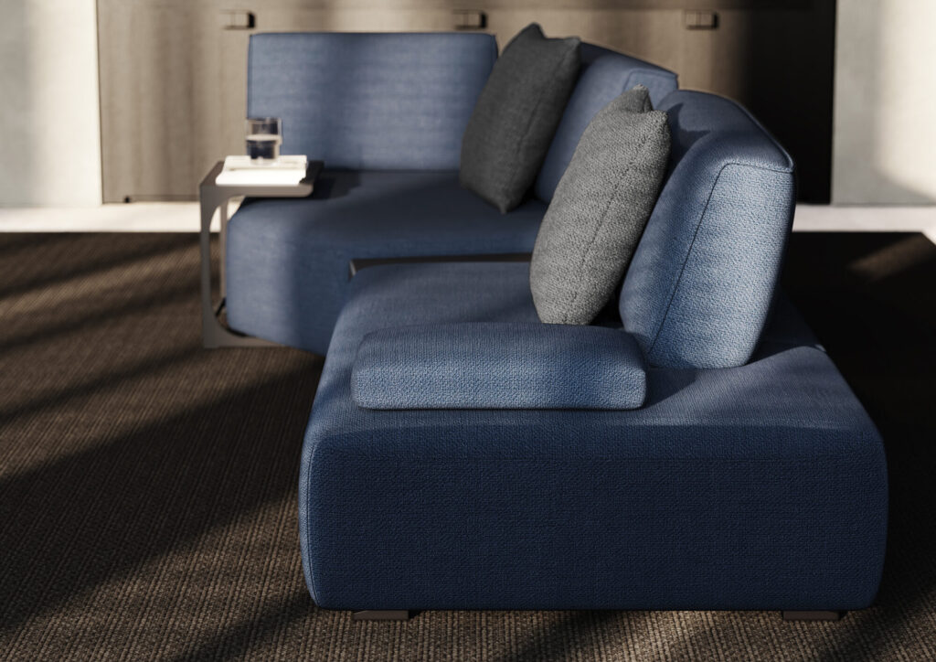 Le Canapé Louise - CR+120 ; TO+50 ; TR+100 ; 2xdeco50X50 en Camino Night est posé sur un tapis à la texture sombre, associé à une petite table d'appoint contenant un verre d'eau et un livre.