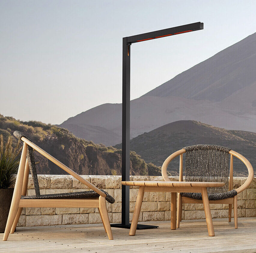 Deux chaises d'extérieur modernes en bois et une lampe haute et mince sont placées sur une terrasse avec des montagnes et des collines en arrière-plan.