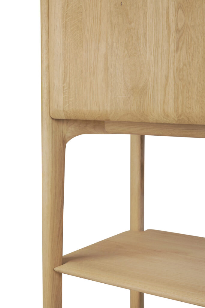 Gros plan d'une armoire PI en chêne naturel avec une étagère inférieure ouverte et des coins arrondis, mettant en valeur le grain et la texture du bois huilé.