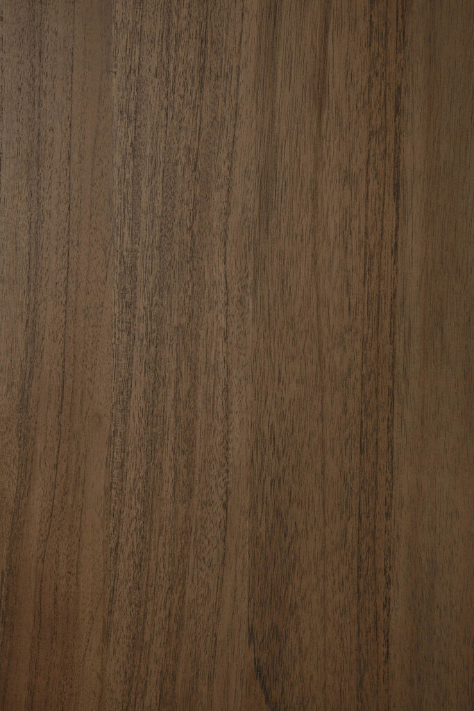 Gros plan sur une surface en bois teck teinté brun, lisse, avec des veines naturelles visibles, parfaite pour un buffet à colonnes ou un meuble à 2 portes.