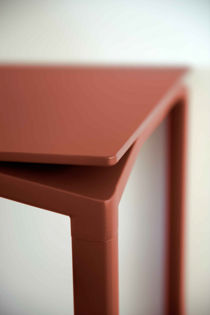 Vue rapprochée de deux pièces modernes empilées de Table Calvi en ocre rouge, aux lignes nettes et anguleuses.