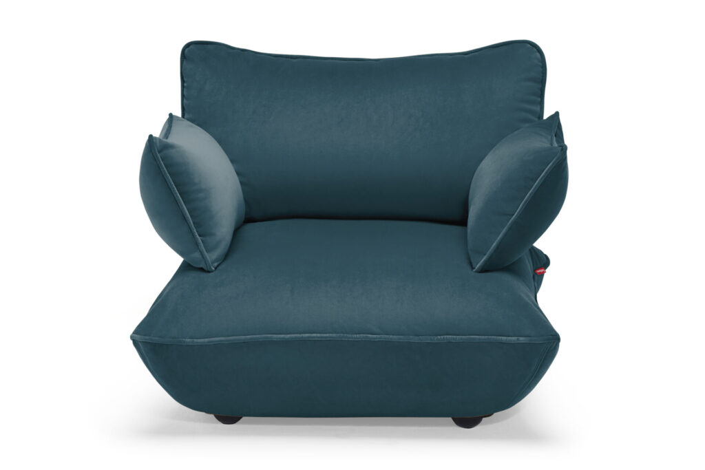 Fauteuil moderne en velours sarcelle avec deux coussins d'appoint assortis, présentés sur un fond blanc.