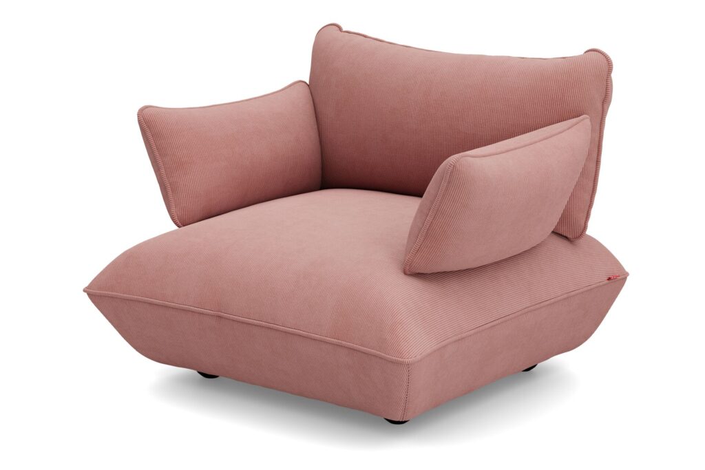 Le Sumo - Loveseat est un fauteuil rose moderne et surdimensionné avec des coussins épais et angulaires et des pieds bas et arrondis, présenté sur un fond blanc.