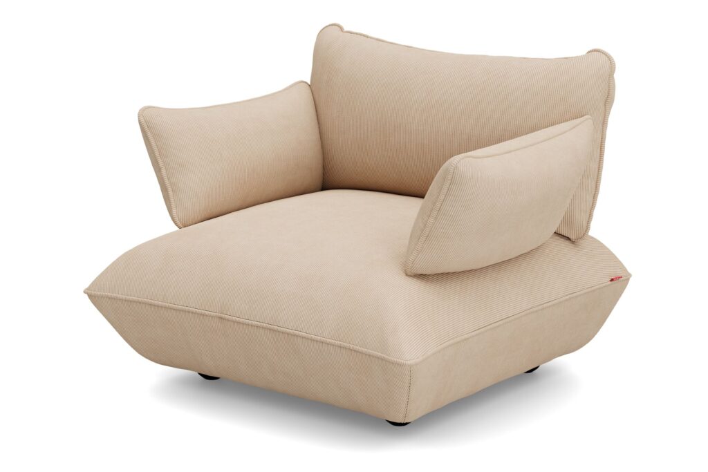La causeuse Sumo présente un design moderne beige avec une assise large et basse, un dossier incliné et deux accoudoirs rembourrés pour un confort moelleux - idéal comme pièce centrale douillette - montré sur un fond blanc uni.