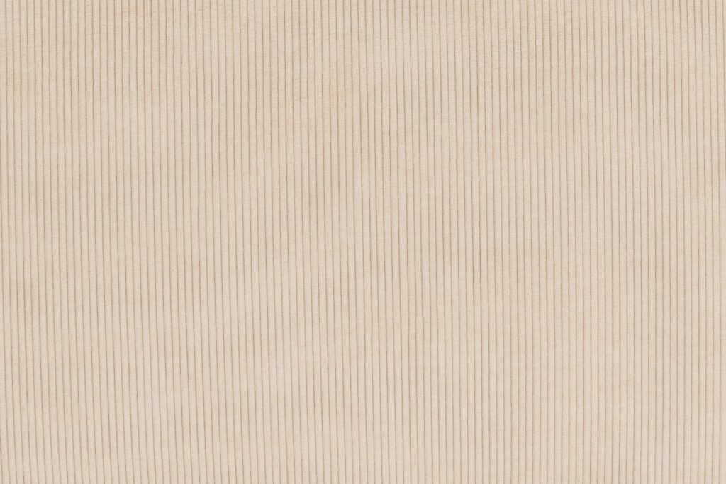 Le Sumo - Loveseat se compose d'un tissu beige avec de fines nervures verticales, offrant un motif subtil et uniforme qui rehausse son aspect raffiné et accueillant.