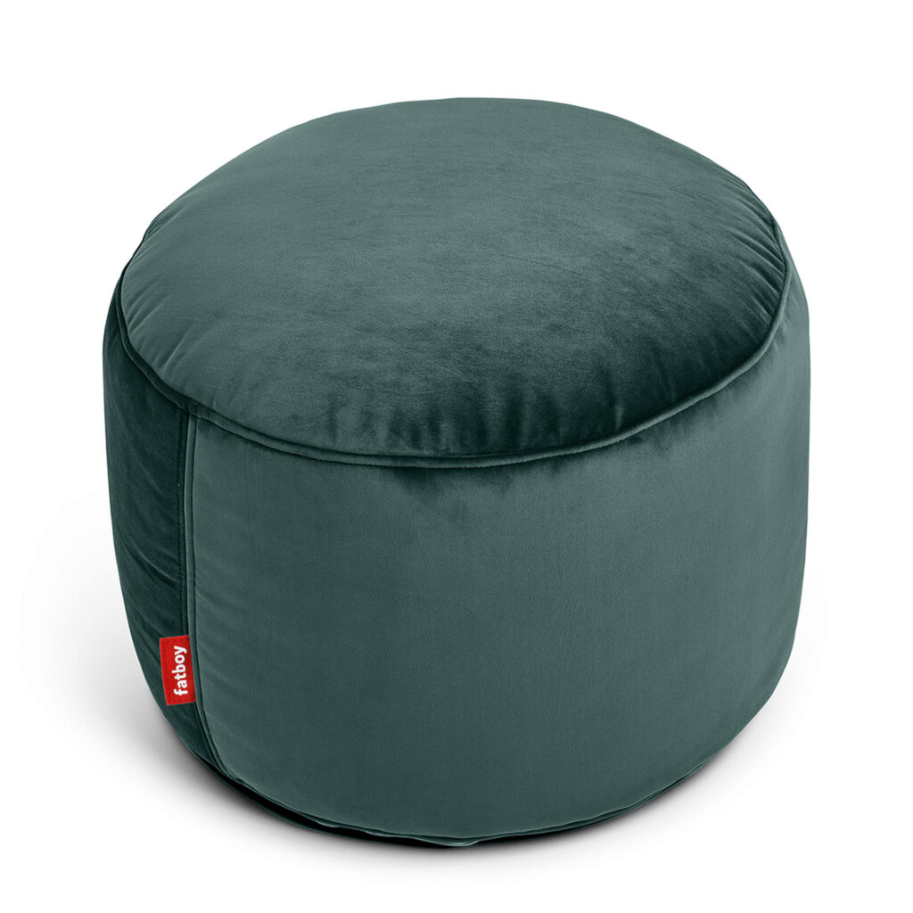 Un pouf rond en velours vert pétrole à la surface lisse, fabriqué à partir de matériaux recyclés, avec une petite étiquette rouge "fatboy" sur le côté.