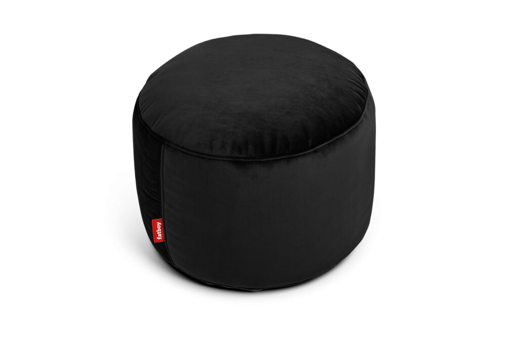 Un pouf rond en velours noir avec une petite étiquette en tissu rouge sur le côté, fabriqué à partir de matériaux recyclés, placé sur un fond blanc.