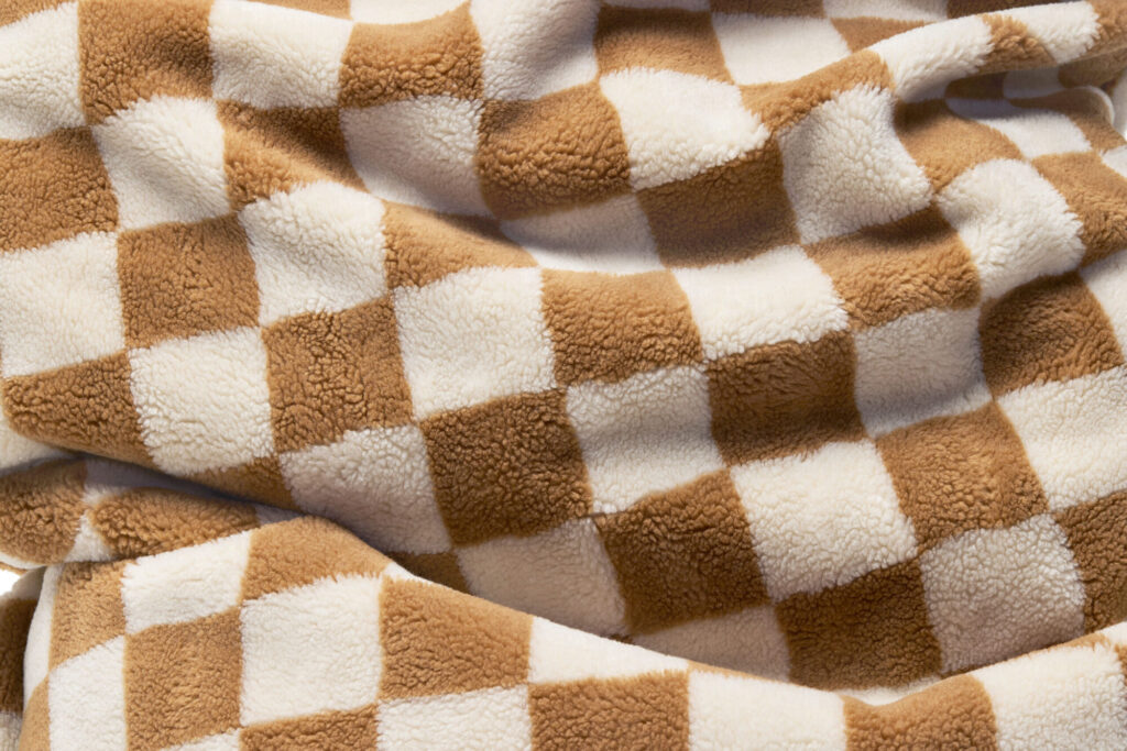 Gros plan sur le Fatboy Point Teddy Chess Almond Creme, dont la matière molletonnée est douce et présente un motif en damier blanc et beige.