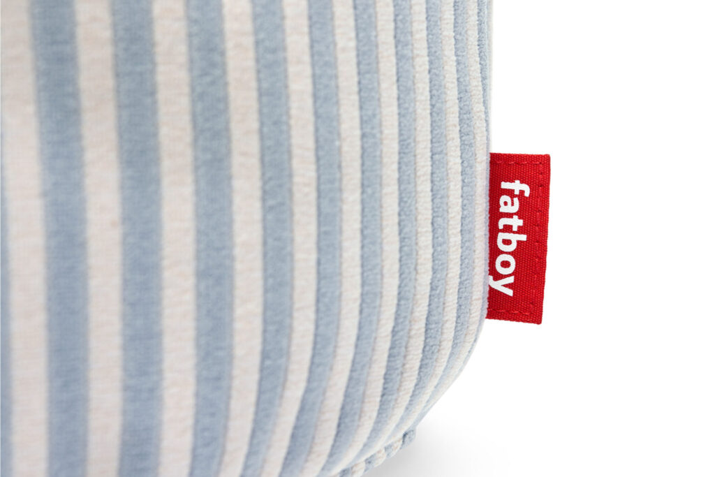 Gros plan sur un tissu rayé bleu et blanc avec une étiquette rouge "fatboy", faisant écho au style ludique de la collection Fatboy Point Terry Cognac Creme.