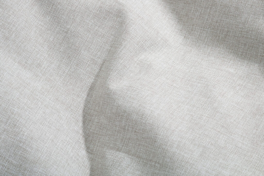 Gros plan sur la toile de lin gris clair Mist, dont la texture est visible et les plis subtils, parfaite pour rehausser les meubles d'extérieur tels que le Paletti Set Small.