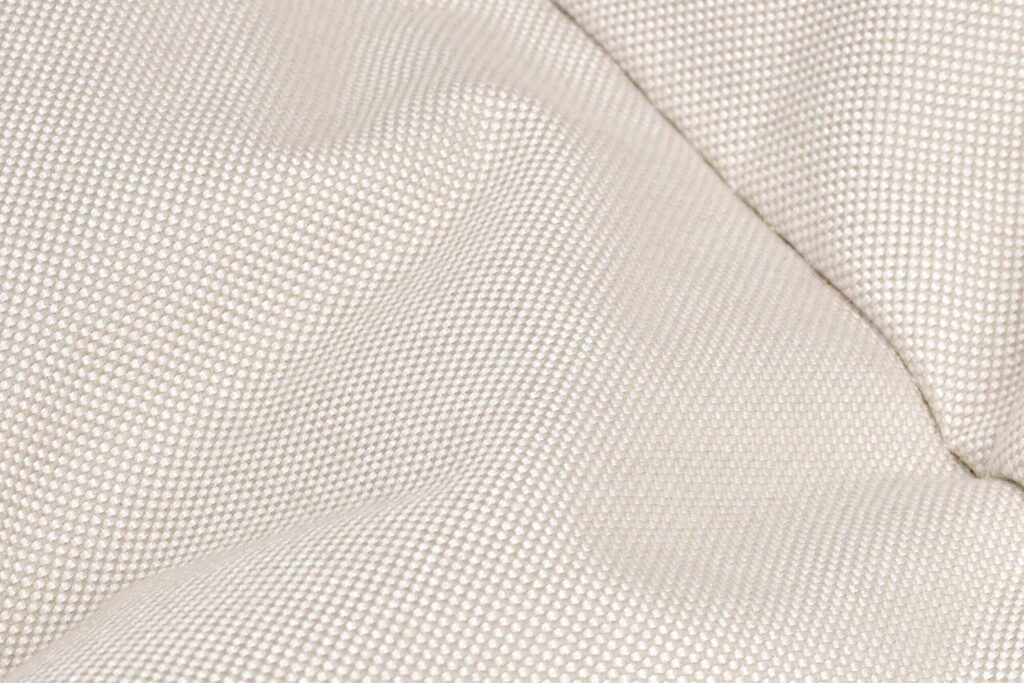 Gros plan d'une surface de tissu texturé beige clair de l'ensemble Paletti en Sahara Medium, présentant de petits points en relief régulièrement espacés et de légers plis.