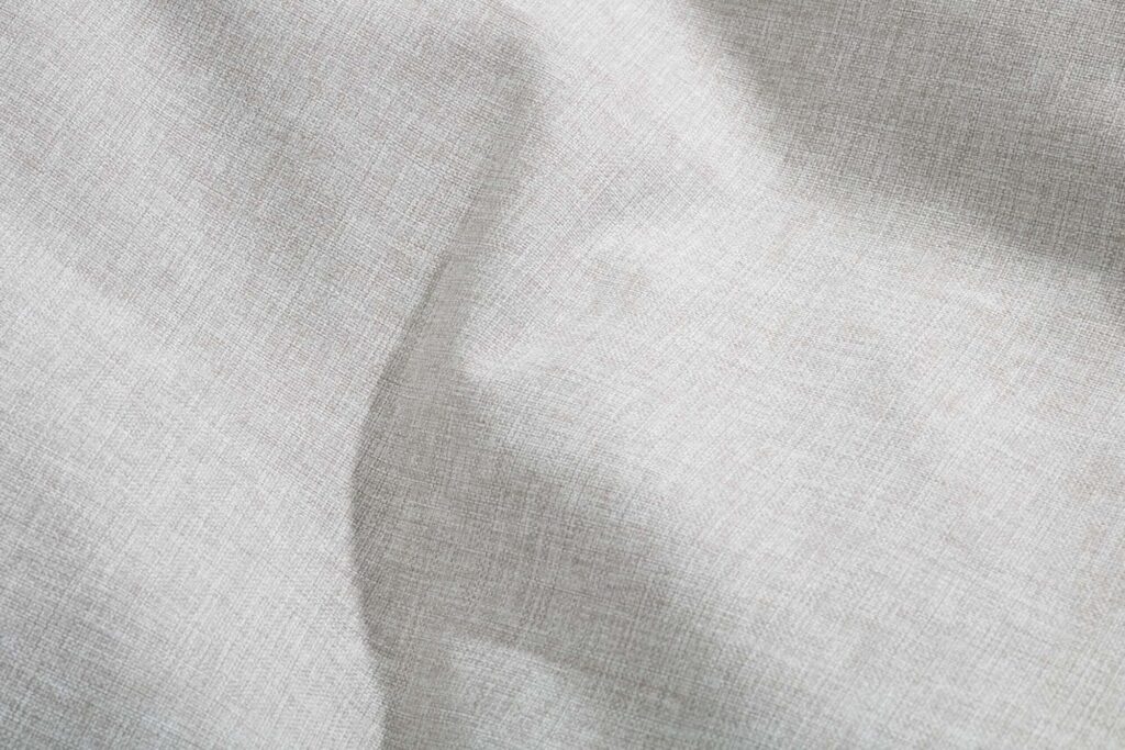 Gros plan sur un tissu texturé gris clair, de couleur brumeuse, dont les fibres sont visibles et les plis légers. Idéal pour l'ensemble Paletti dans les grandes tailles.