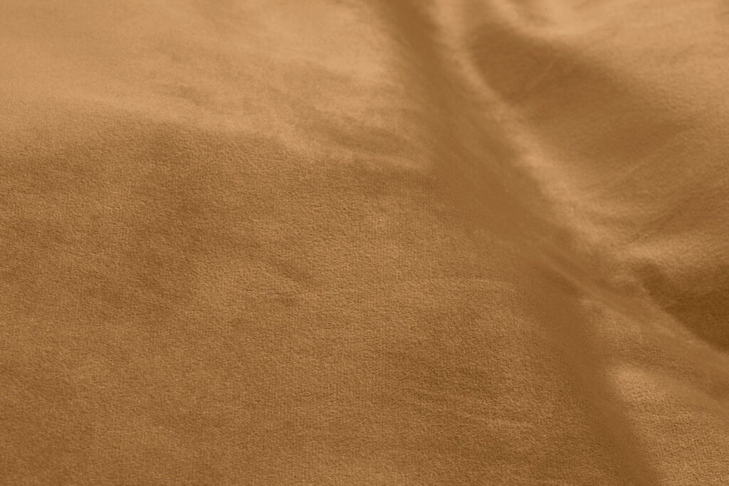 Vue rapprochée d'une surface lisse en velours marron clair recyclé avec des plis doux et une texture subtile, parfaite pour un siège d'angle Sumo.