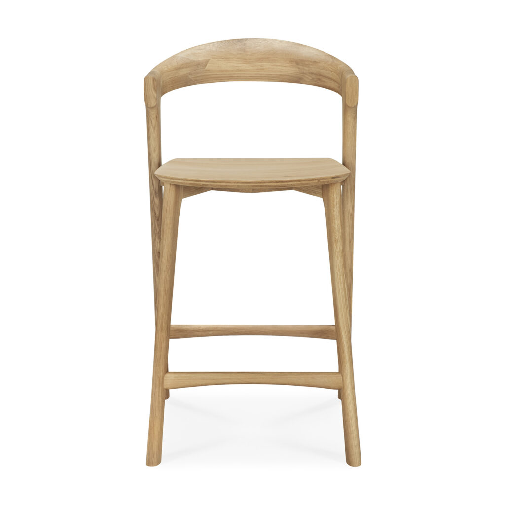 Le tabouret de bar Bok se caractérise par une structure en bois avec un dossier incurvé, une assise carrée et quatre pieds reliés par des supports horizontaux, présentés sur fond blanc.