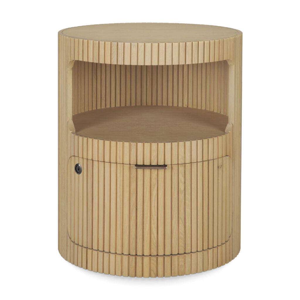 Table de nuit ronde en chêne naturel avec rainures verticales, comprenant une étagère ouverte et un meuble fermé - style Boomerang de Caisson - avec une petite poignée et une serrure sur le côté inférieur gauche.