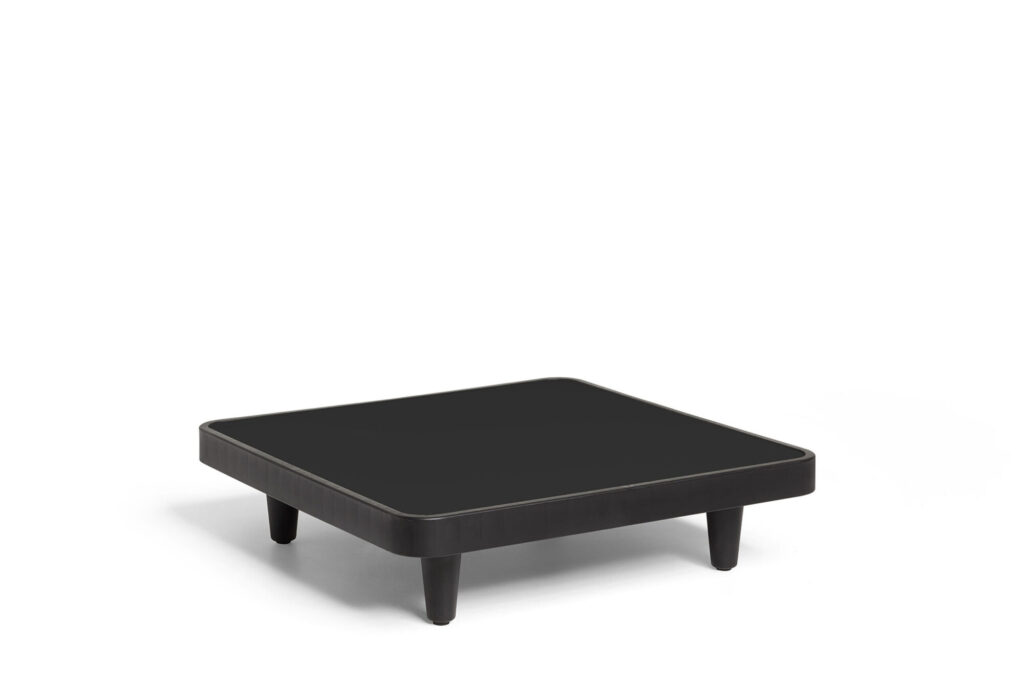Une table Paletti anthracite, basse et carrée avec des bords arrondis et quatre pieds courts, se détache sur un fond blanc uni.