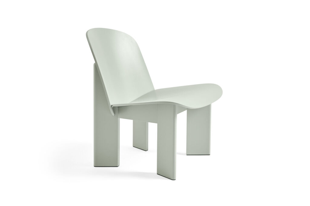 Une chaise minimaliste gris clair avec trois pieds larges et plats et une assise et un dossier incurvés, rappelant un design moderne de ciseau, photographiée sur un fond blanc.